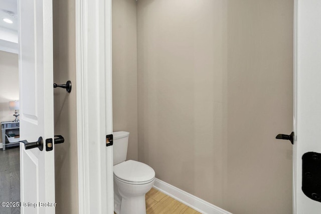 bathroom with toilet, baseboards, and wood finished floors