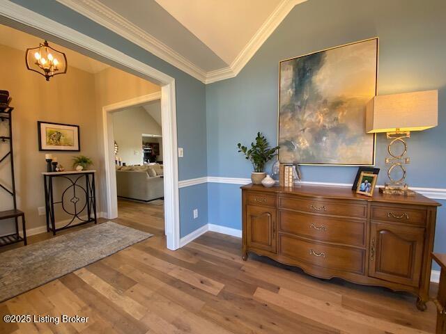 interior space with crown molding, lofted ceiling, a chandelier, and light hardwood / wood-style floors