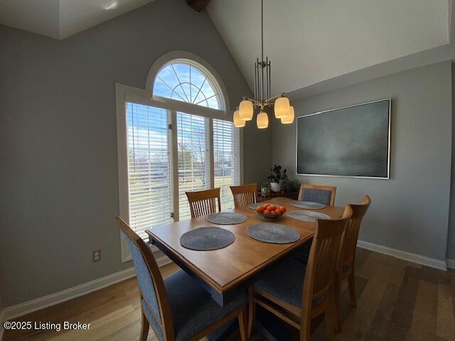 dining space featuring hardwood / wood-style flooring, high vaulted ceiling, and a notable chandelier