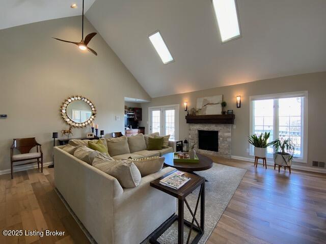 living room with high vaulted ceiling, a fireplace, light hardwood / wood-style floors, and ceiling fan