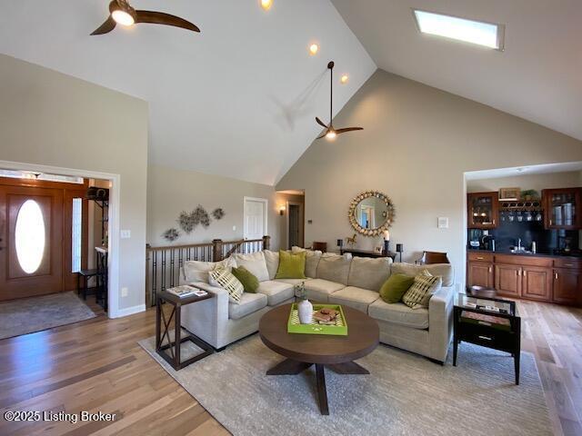 living room featuring hardwood / wood-style flooring, ceiling fan, sink, and high vaulted ceiling