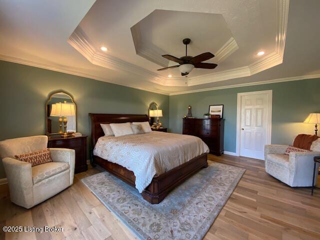 bedroom featuring a raised ceiling, ornamental molding, ceiling fan, and light wood-type flooring