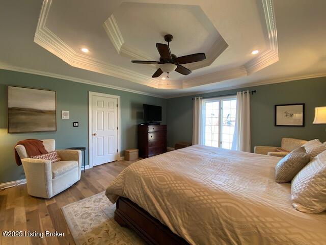 bedroom featuring hardwood / wood-style flooring, ornamental molding, a raised ceiling, and ceiling fan