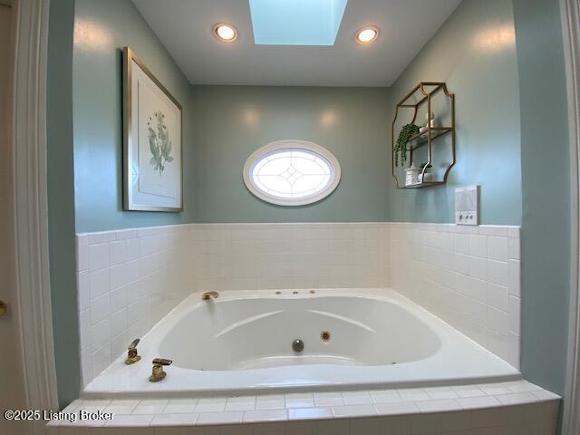 bathroom featuring tiled bath and a skylight