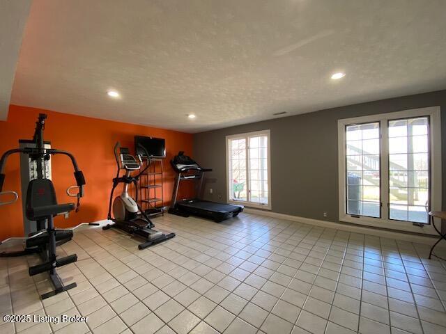 exercise room with light tile patterned floors and a textured ceiling