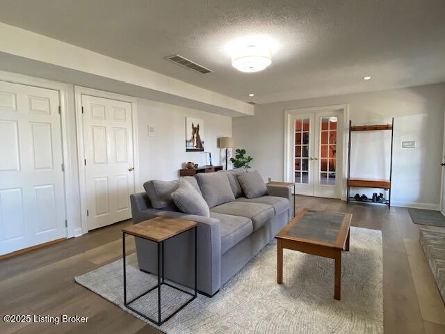 living room with french doors, dark hardwood / wood-style floors, and a textured ceiling