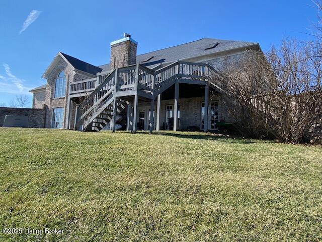 back of property featuring a wooden deck and a lawn