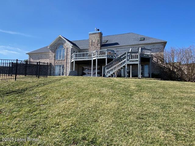 rear view of house featuring a wooden deck and a lawn