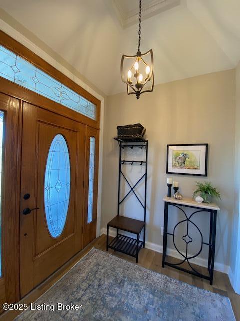 entrance foyer featuring dark hardwood / wood-style flooring, a notable chandelier, and vaulted ceiling