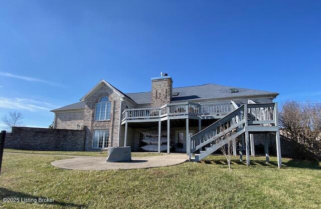 rear view of house featuring a wooden deck, a patio area, and a lawn