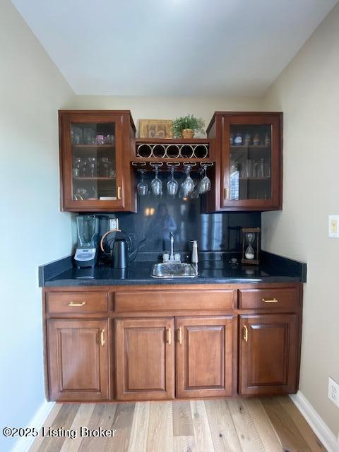 bar with sink, decorative backsplash, and light hardwood / wood-style flooring