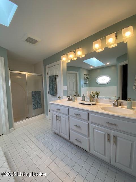 bathroom with walk in shower, tile patterned floors, vanity, and a skylight