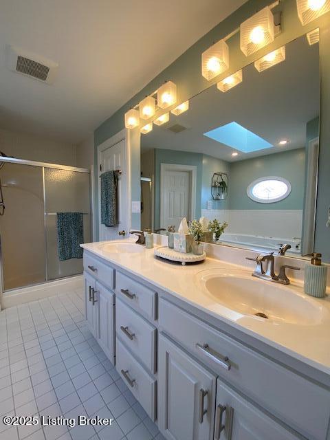 bathroom featuring vanity, a shower with shower door, tile patterned floors, and a skylight