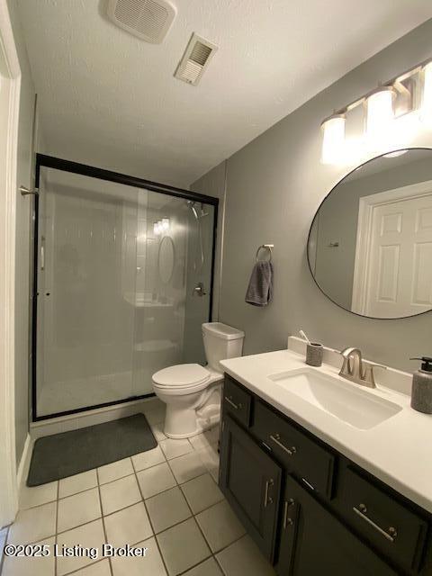 bathroom with a shower with shower door, tile patterned flooring, vanity, toilet, and a textured ceiling