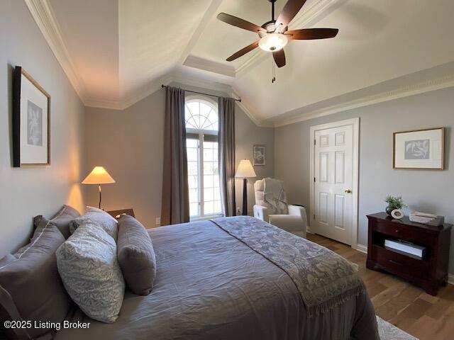 bedroom featuring lofted ceiling, hardwood / wood-style flooring, ornamental molding, and ceiling fan