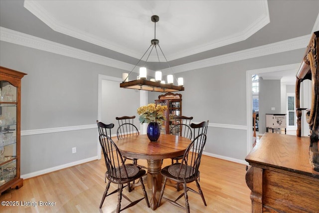 dining room with a notable chandelier, crown molding, light hardwood / wood-style flooring, and a raised ceiling