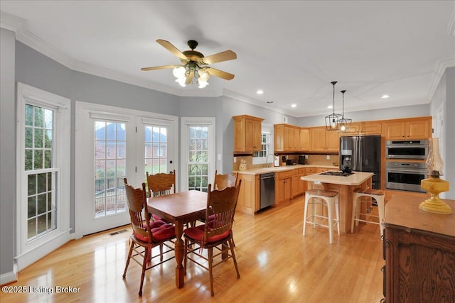 dining area featuring ceiling fan, ornamental molding, sink, and light hardwood / wood-style floors