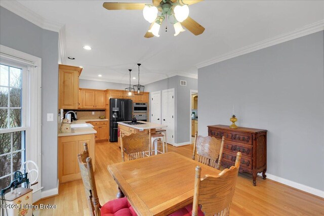 dining room with sink, crown molding, and light hardwood / wood-style floors