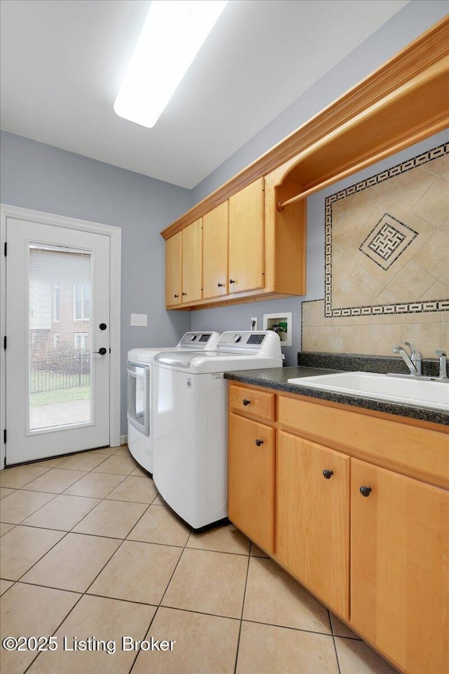 laundry room featuring sink, light tile patterned floors, washer and clothes dryer, and cabinets