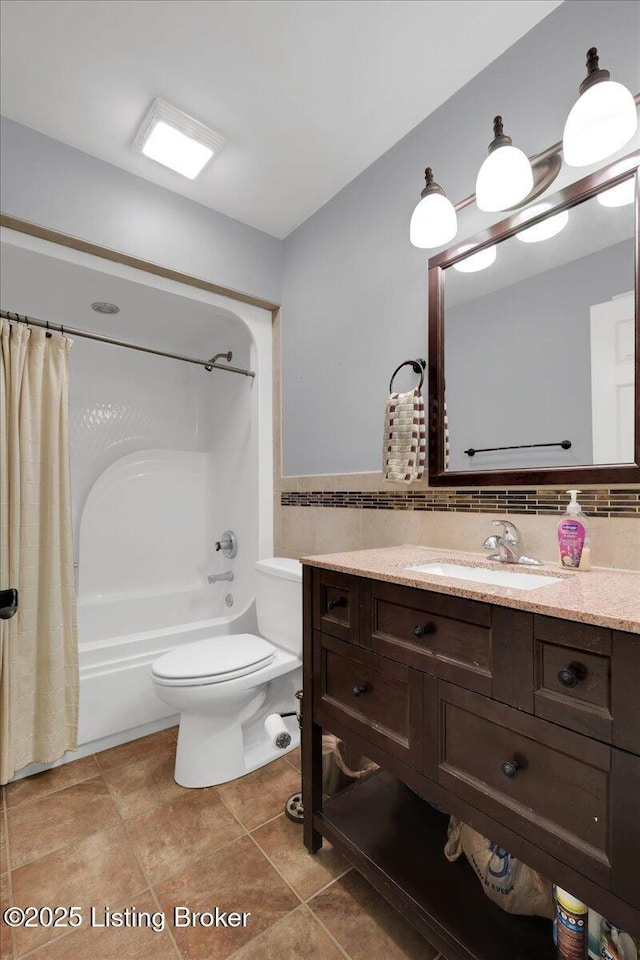 full bathroom featuring toilet, tile walls, vanity, shower / bath combo with shower curtain, and tile patterned flooring