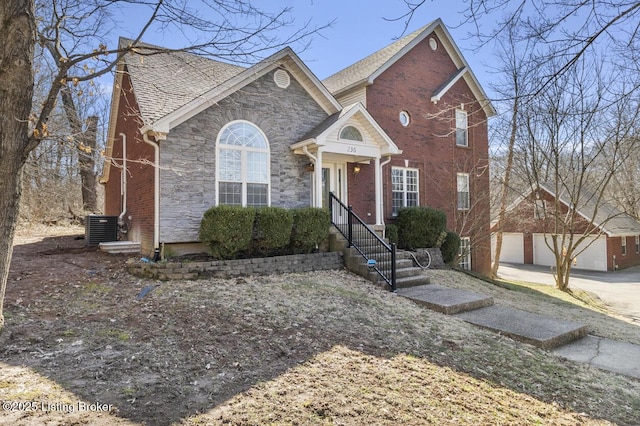 view of front of house featuring brick siding, central air condition unit, a garage, stone siding, and an outdoor structure