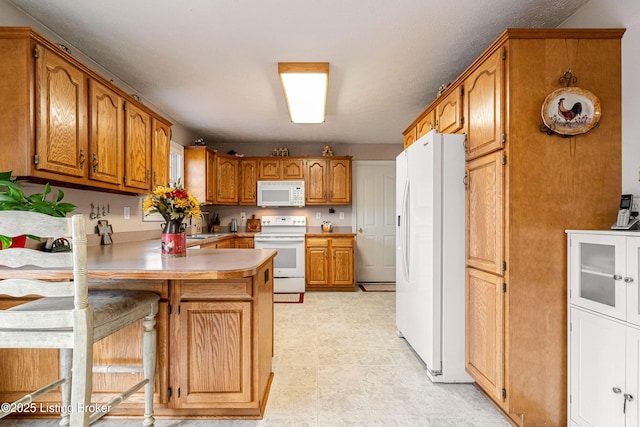 kitchen featuring a breakfast bar, white appliances, and kitchen peninsula