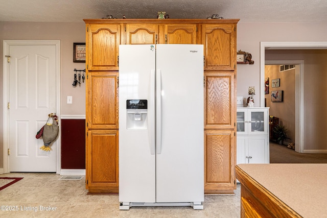 kitchen featuring white fridge with ice dispenser and a textured ceiling