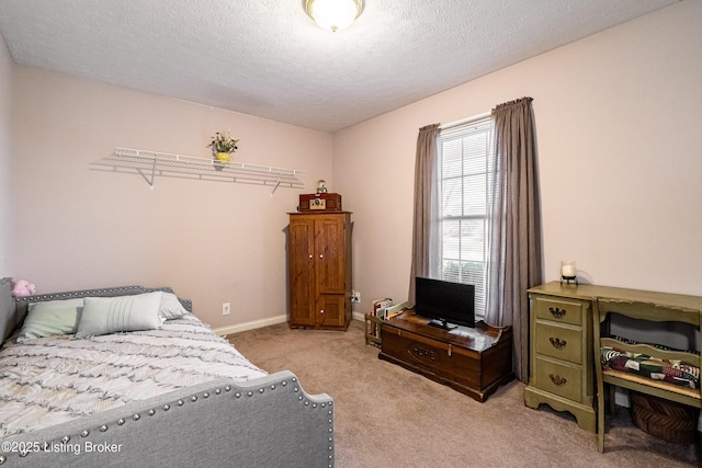 bedroom with light colored carpet and a textured ceiling