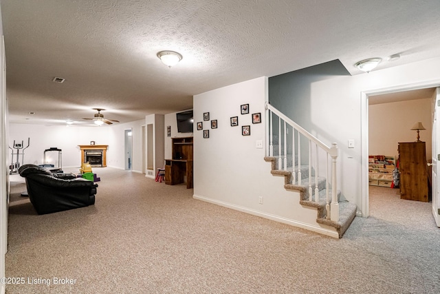 carpeted living room with ceiling fan and a textured ceiling