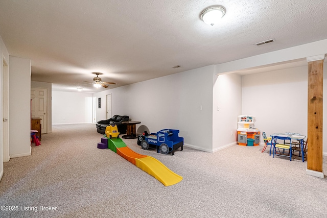 recreation room with ceiling fan, carpet, and a textured ceiling