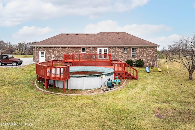 back of house featuring a pool side deck, a playground, and a lawn