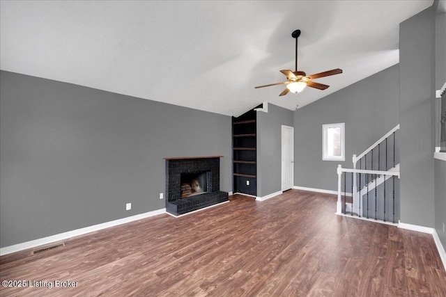 unfurnished living room with dark wood-type flooring, lofted ceiling, a fireplace, and built in shelves