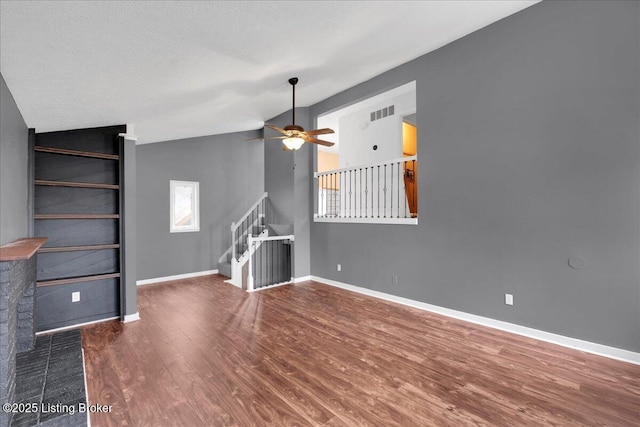 unfurnished living room with ceiling fan, lofted ceiling, hardwood / wood-style floors, and a textured ceiling