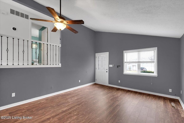 empty room featuring lofted ceiling, ceiling fan, dark wood-type flooring, and a textured ceiling