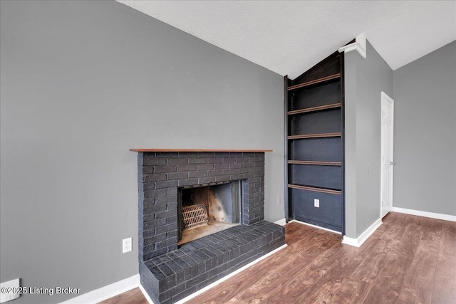 unfurnished living room with built in features, a fireplace, a textured ceiling, dark hardwood / wood-style flooring, and vaulted ceiling