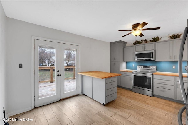 kitchen with french doors, butcher block counters, gray cabinetry, light wood-type flooring, and appliances with stainless steel finishes