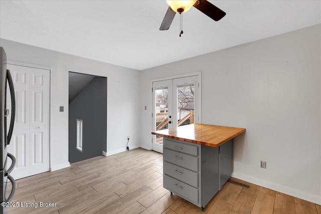 kitchen with butcher block countertops, light hardwood / wood-style flooring, stainless steel fridge, gray cabinets, and ceiling fan