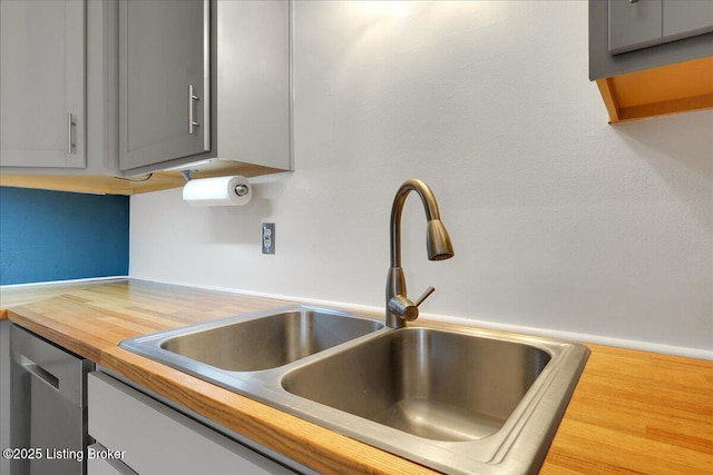 kitchen with butcher block counters, sink, gray cabinets, and dishwasher