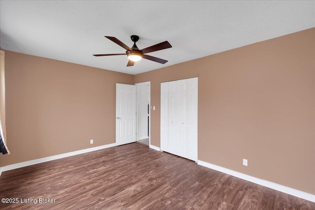 unfurnished bedroom featuring a closet, dark hardwood / wood-style floors, a textured ceiling, and ceiling fan