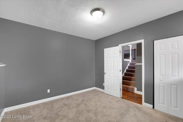 unfurnished bedroom featuring light carpet, a textured ceiling, and a closet