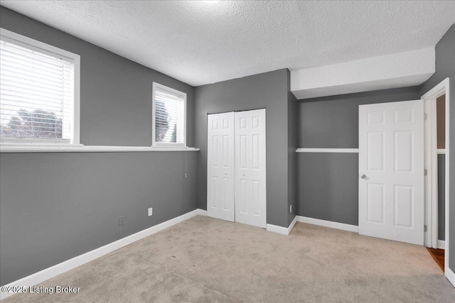 unfurnished bedroom with a closet, light carpet, and a textured ceiling