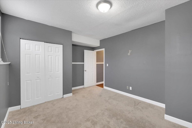 unfurnished bedroom with light colored carpet, a closet, and a textured ceiling