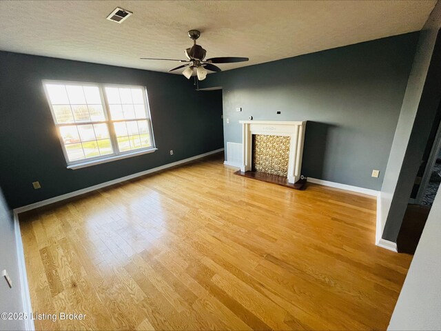 223 Lea Ct, Rineyville, KY 40162 - unfurnished living room with visible vents, light wood-style flooring, a fireplace, baseboards, and ceiling fan