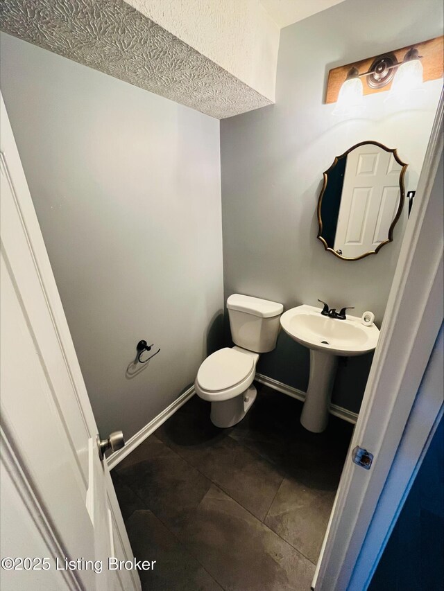 223 Lea Ct, Rineyville, KY 40162 - half bathroom featuring tile patterned floors, toilet, baseboards, and a textured ceiling