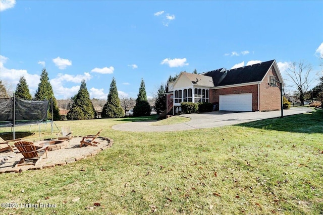 exterior space with a front yard, an outdoor fire pit, a trampoline, and a garage