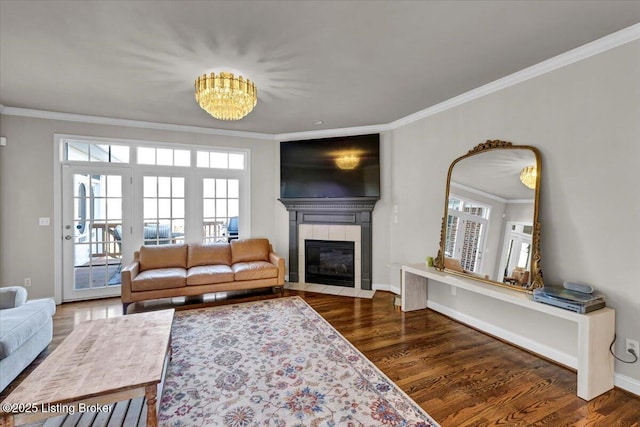 living room with an inviting chandelier, a fireplace, ornamental molding, and dark hardwood / wood-style flooring