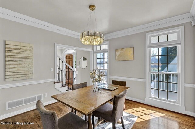 dining space featuring an inviting chandelier, ornamental molding, and hardwood / wood-style floors