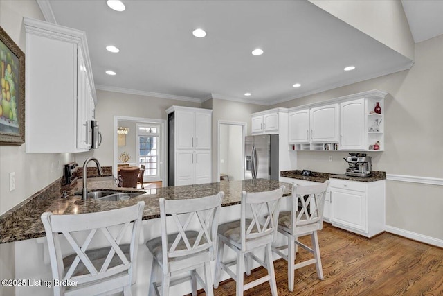 kitchen with appliances with stainless steel finishes, a breakfast bar, white cabinetry, sink, and kitchen peninsula