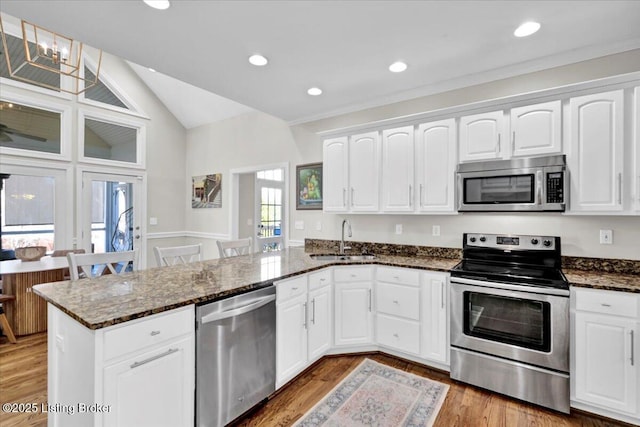 kitchen with stainless steel appliances, sink, white cabinets, and kitchen peninsula