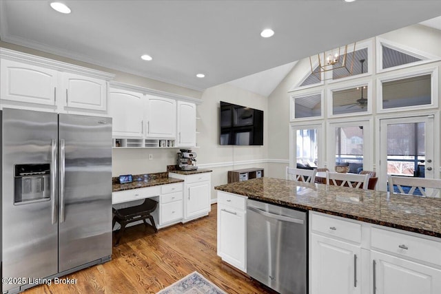 kitchen with appliances with stainless steel finishes, white cabinets, light hardwood / wood-style floors, and dark stone counters